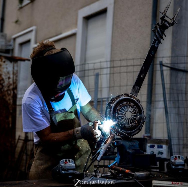 Une artiste en train de souder des matériaux de récupération pour créer son œuvre